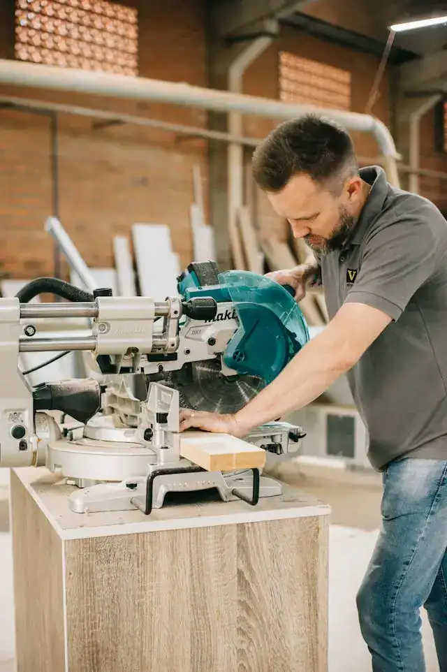 man using mitre saw in workshop
